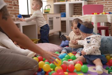 Group of toddlers playing with toys sitting on floor at kindergarten